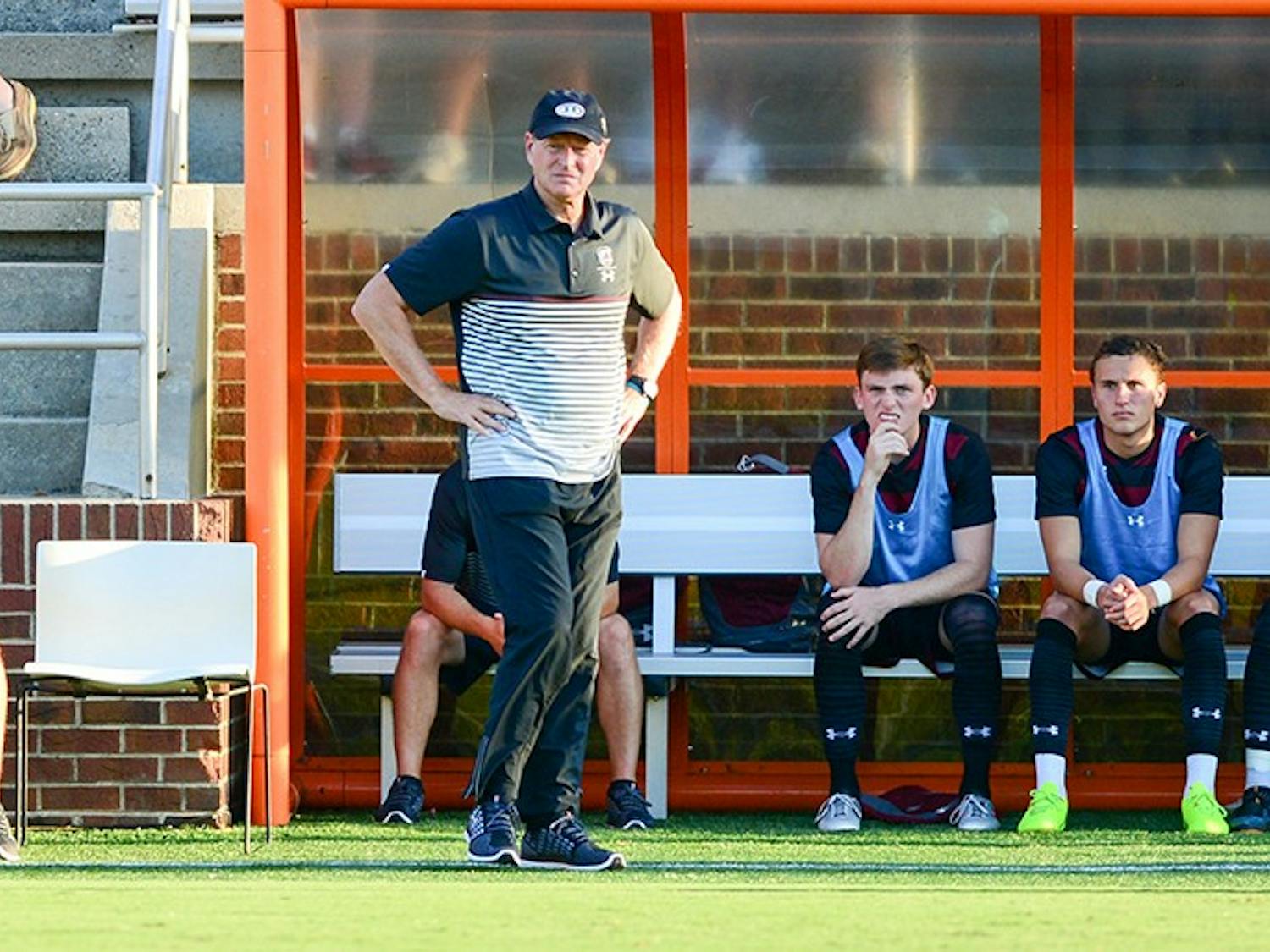  Mark Berson, head coach of South Carolina men’s soccer, stands in front of his player sitting on the bench. 