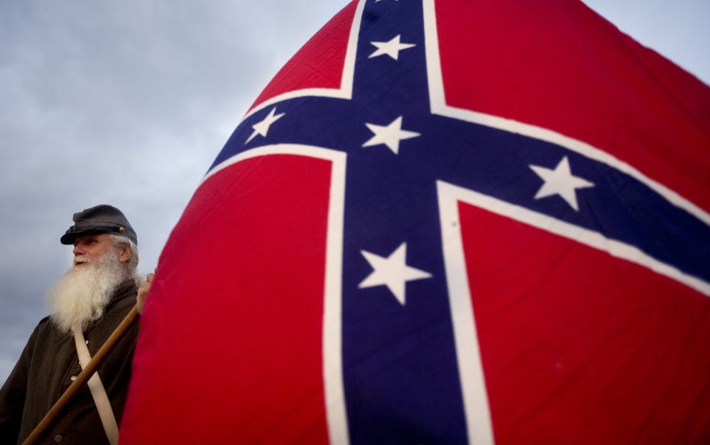 Dale Smith, 60, of Johnsonville, South Carolina, holds a Confederate flag as he looks out to Fort Sumter from the Battery in downtown Charleston, South Carolina, as they wait for cannons to be fired to mark the 150th anniversary of the start of the Civil War, Tuesday, April 12, 2011. (C. Aluka Berry/The State/MCT)