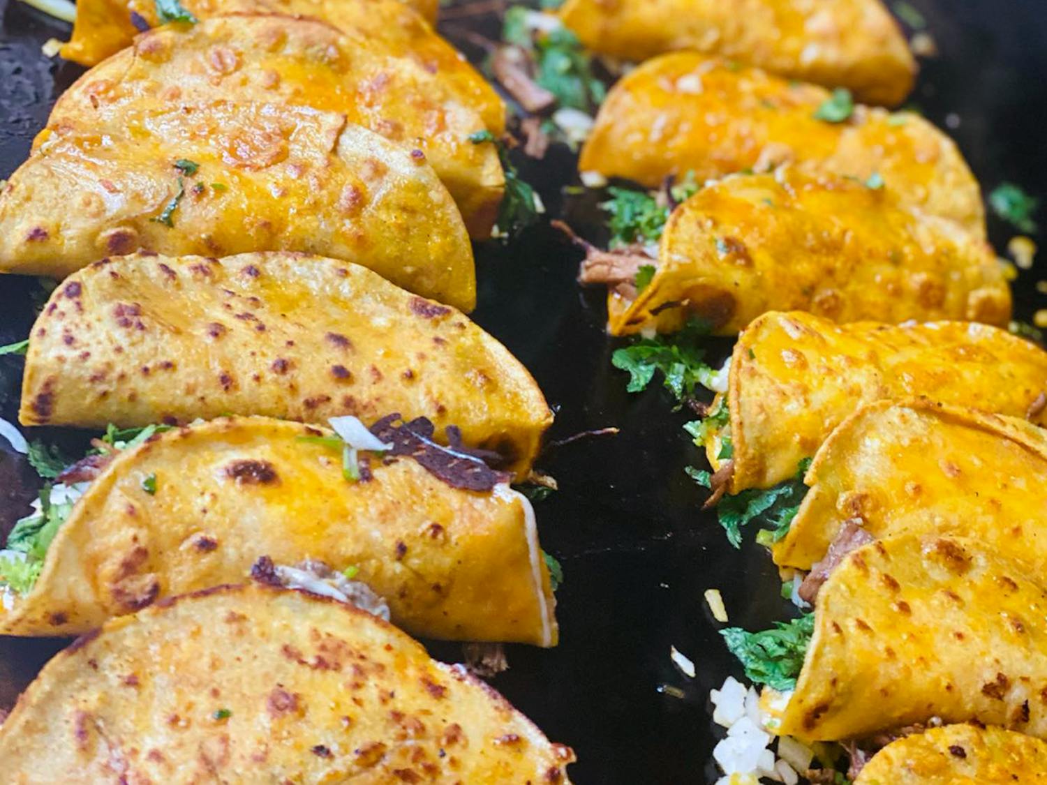 Birria tacos being made at Real Mexico Restaurant in Columbia, SC. In order to make birria tacos, tortillas are first soaked in a broth called consomme, and then grilled to become crispy. The color of the tortillas comes from consomme.