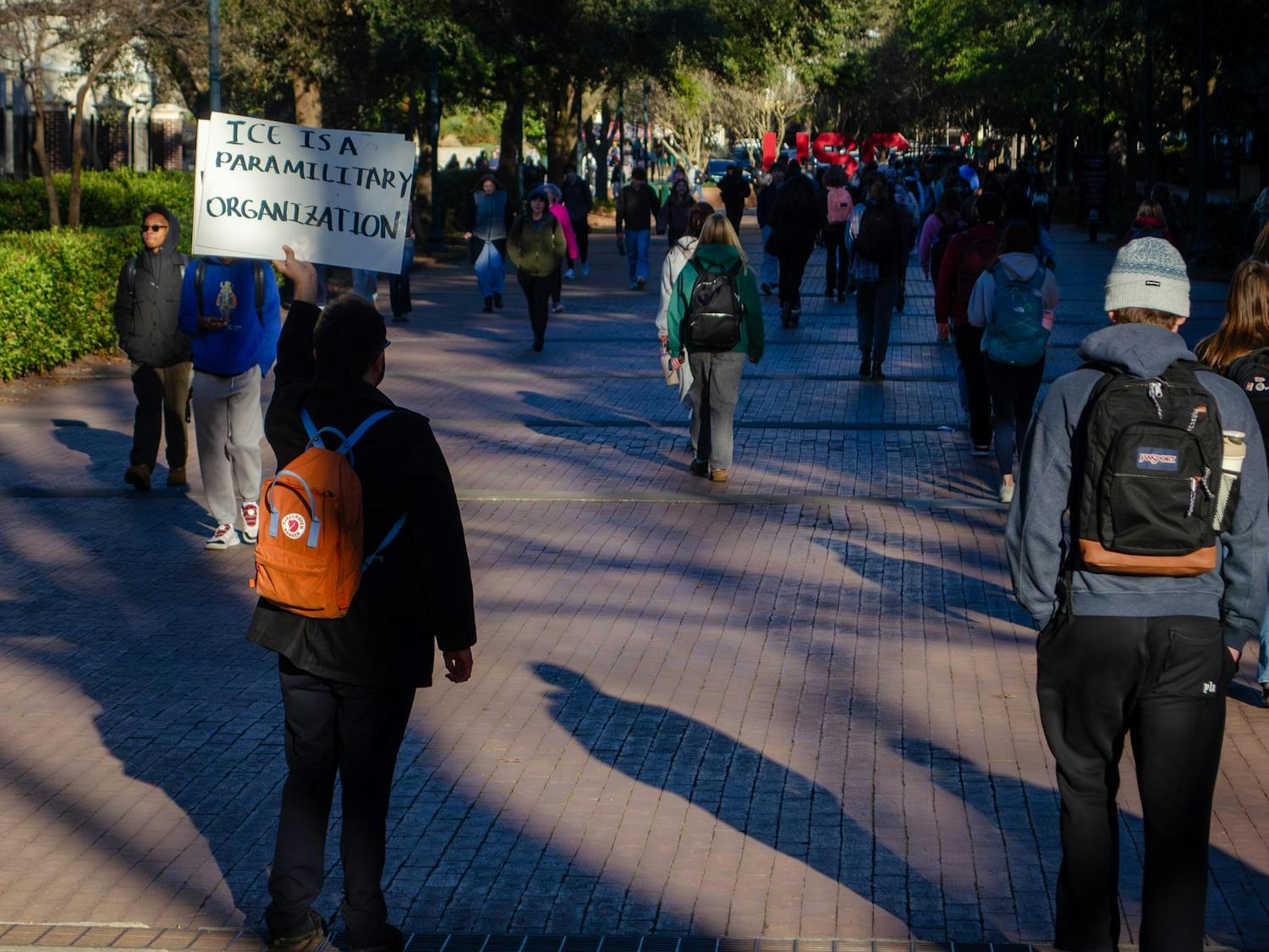 A student, who did not give their name, holds a sign that calls U.S. Immigration and Customs Enforcement a “paramilitary organization” on the bridge across Pickens Street in Columbia, South Carolina, on Jan. 20, 2026. The reverse of the sign says, “human rights are in danger.”