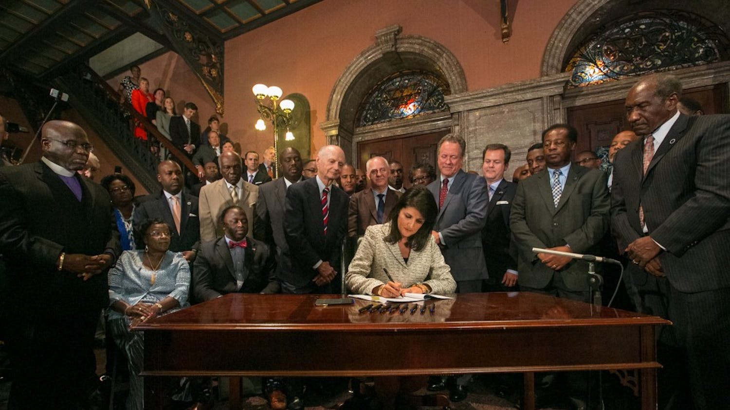 South Carolina Gov. Nikki Haley, surrounded by three former governors, some family members of the slain nine and many legislators, signs the bill to remove the Confederate flag from the South Carolina State House grounds on Thursday, July 9, 2015, in Columbia, S.C. (Tim Dominick/The State/TNS)