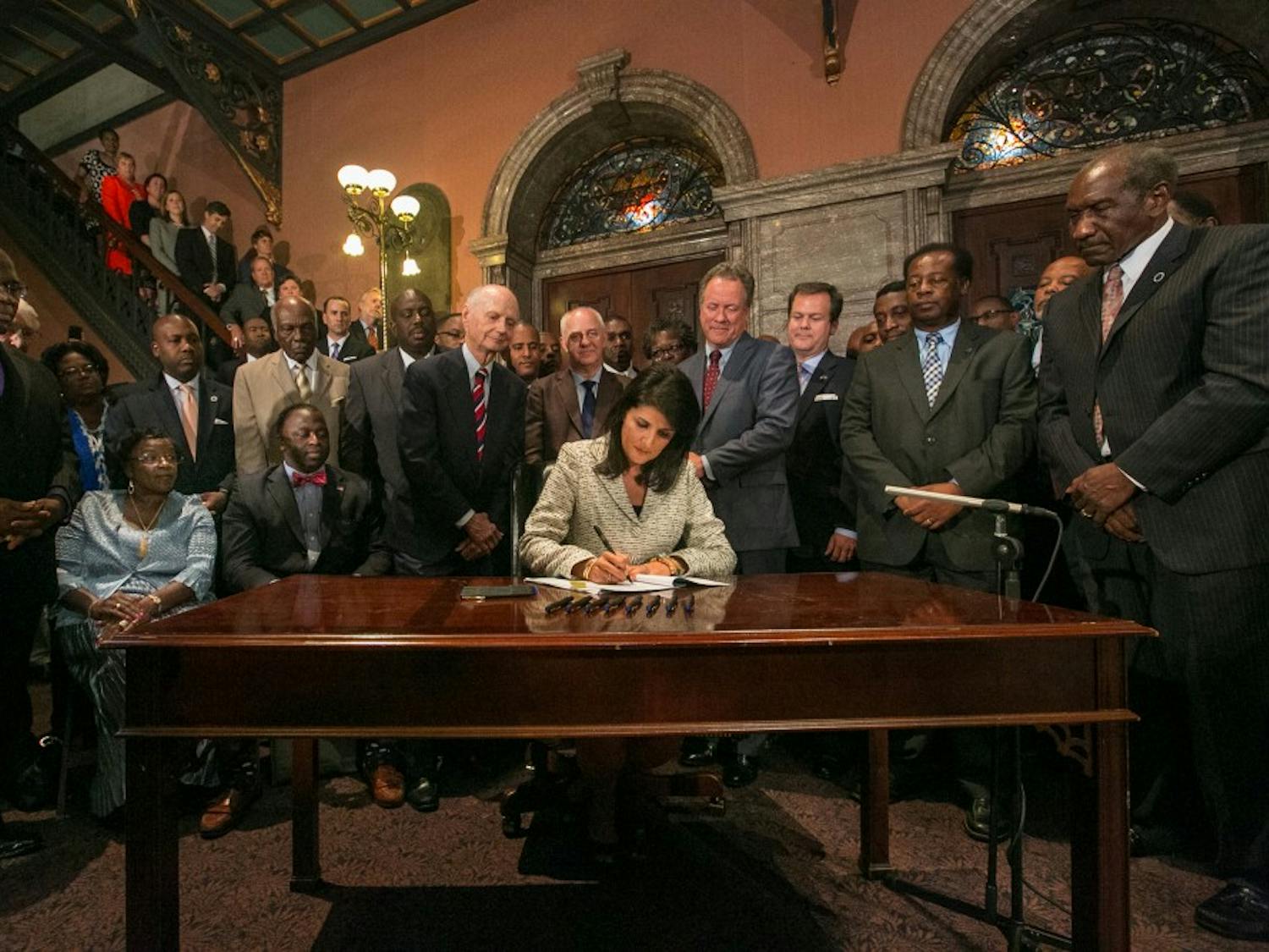 South Carolina Gov. Nikki Haley, surrounded by three former governors, some family members of the slain nine and many legislators, signs the bill to remove the Confederate flag from the South Carolina State House grounds on Thursday, July 9, 2015, in Columbia, S.C. (Tim Dominick/The State/TNS)