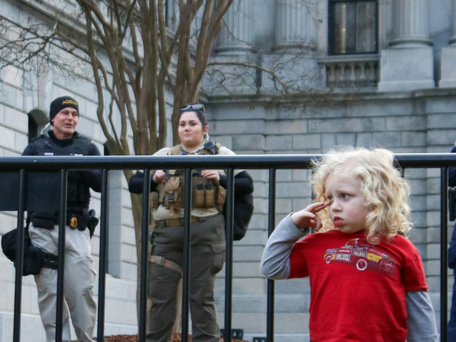 Law enforcement stayed on the inside of the fence, keeping watch over the remaining crowd of people attending Trump's first campaign stop on Jan. 28, 2023. The child (right) witnessed one of the few verbal altercations of the day.&nbsp;