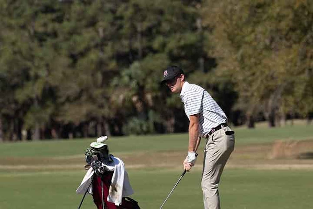A starting player for the South Carolina golf team looks ahead as he prepares to hit the ball.