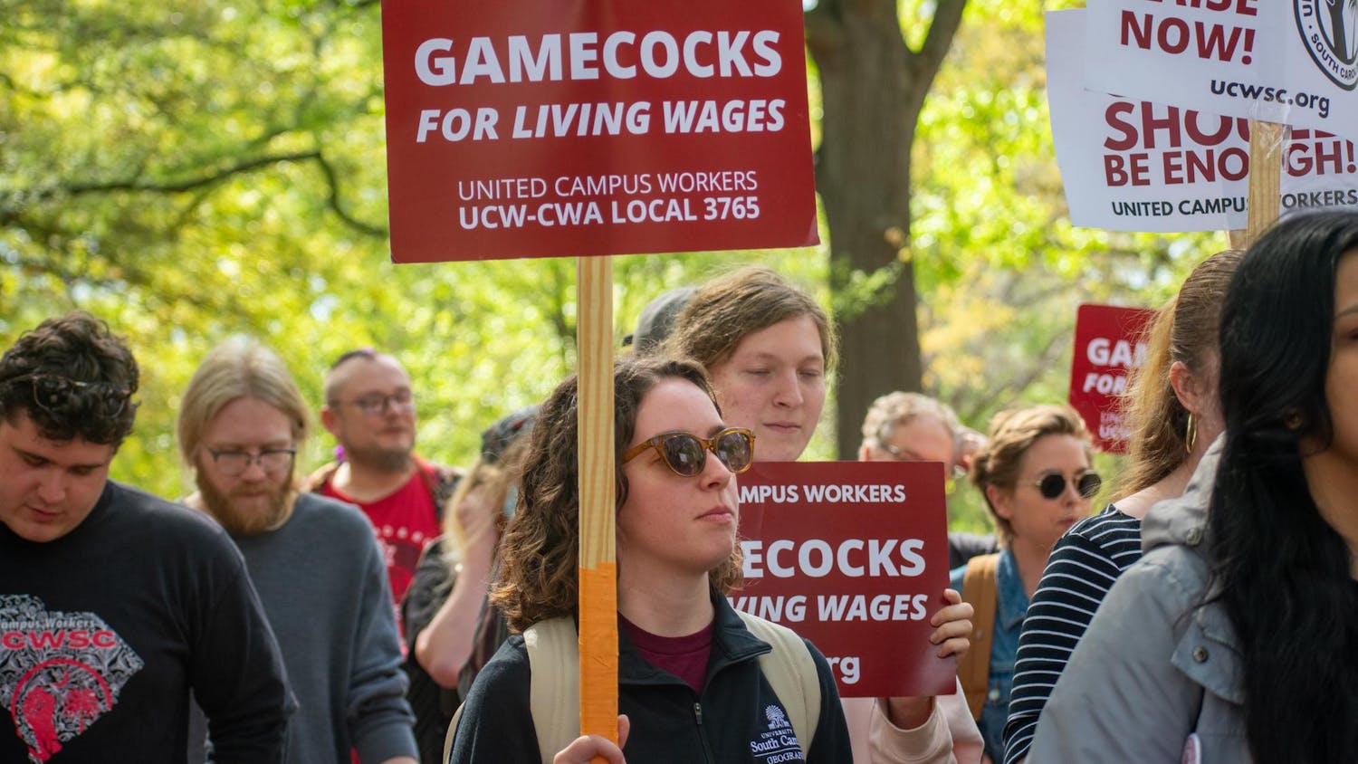 A supporter of the United Campus Workers holds a picket sign reading "Gamecocks for living wages" as the group marches toward the Osborne Administrative Building on March 28, 2024. The union created a petition urging that USC makes annual cost of living adjustments to the wages of all university workers.
