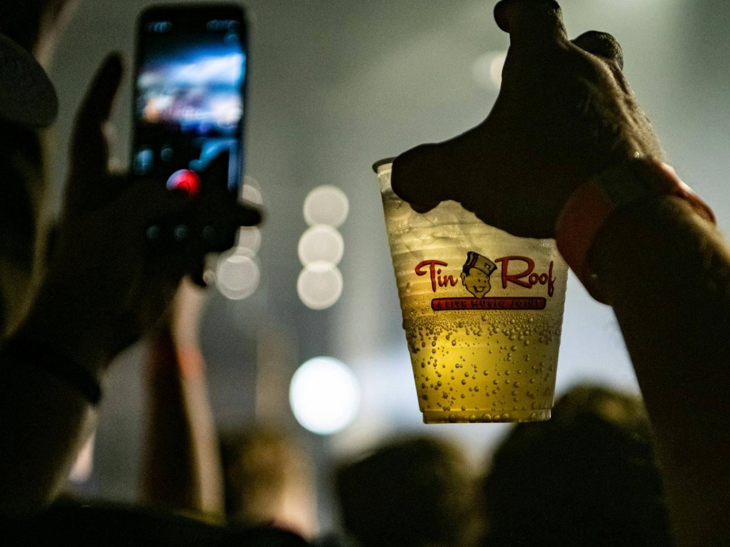 A fan holds a cup of beer and records a video during the Matt and Kim concert Nov. 17, 2019 at The Senate. The Senate offers a full bar and allows food purchased at Tin Roof next door to be brought over to the concert venue.