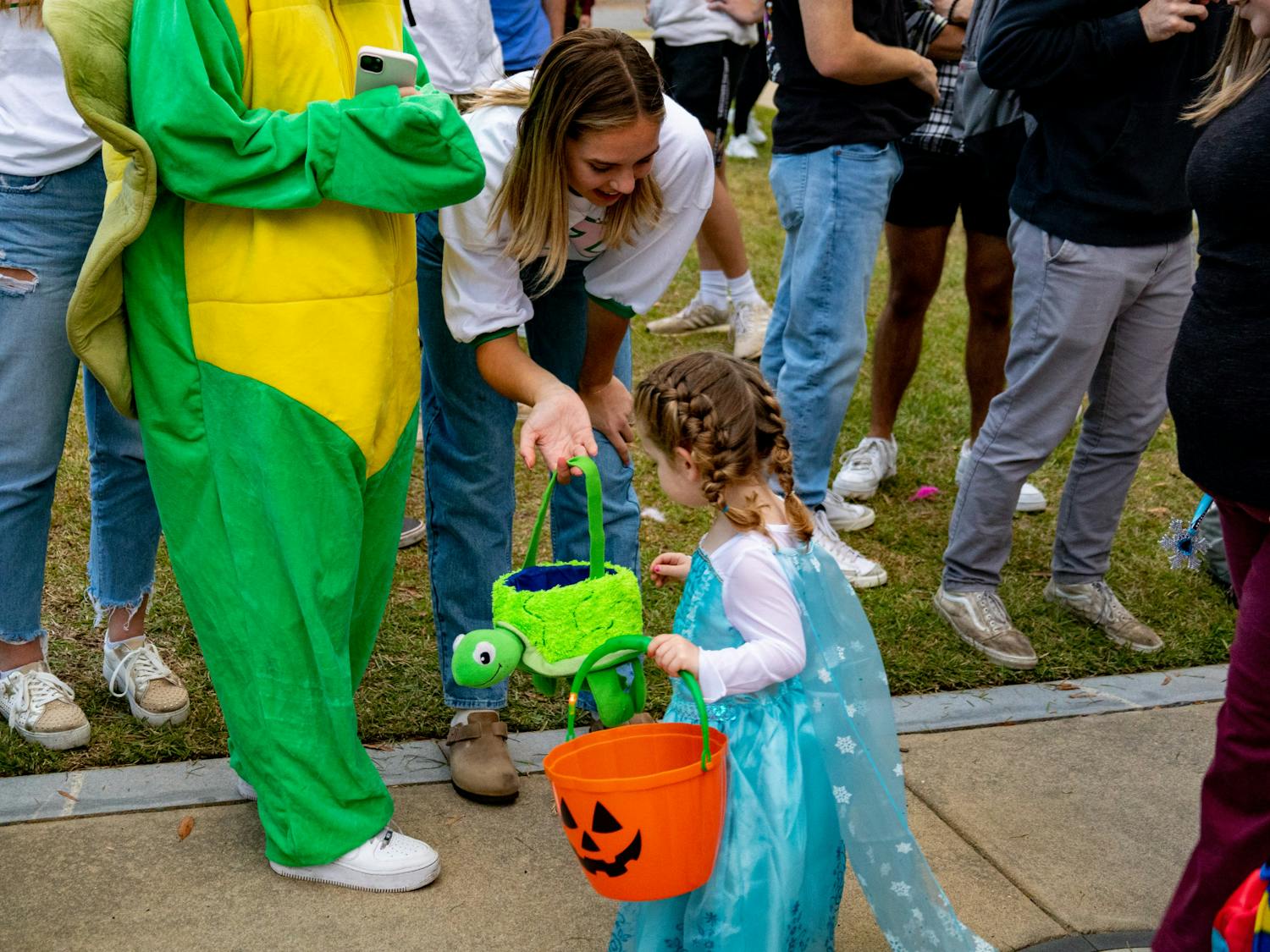 A sorority member hands out candy to a young trick or treater for the Trick or Treat with Greek Halloween event on Oct. 25, 2022. Community members gathered in Greek Village for a community outreach event held by the chapters of USC's sororities and fraternities.