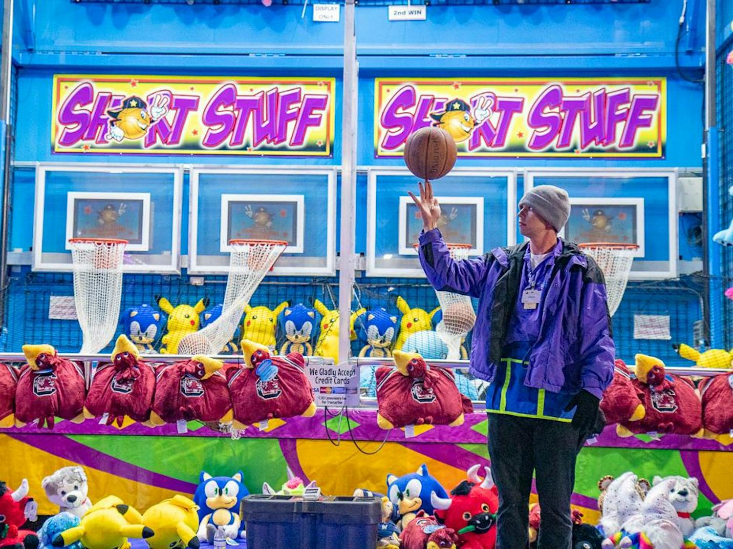 Zach Mayfield, 25, spins a basketball on his finger in front of his carnival game at the South Carolina State Fair on Oct. 18, 2023. Mayfield is from Ocala, Florida, and has worked at two fairs in the United States and one in Canada.