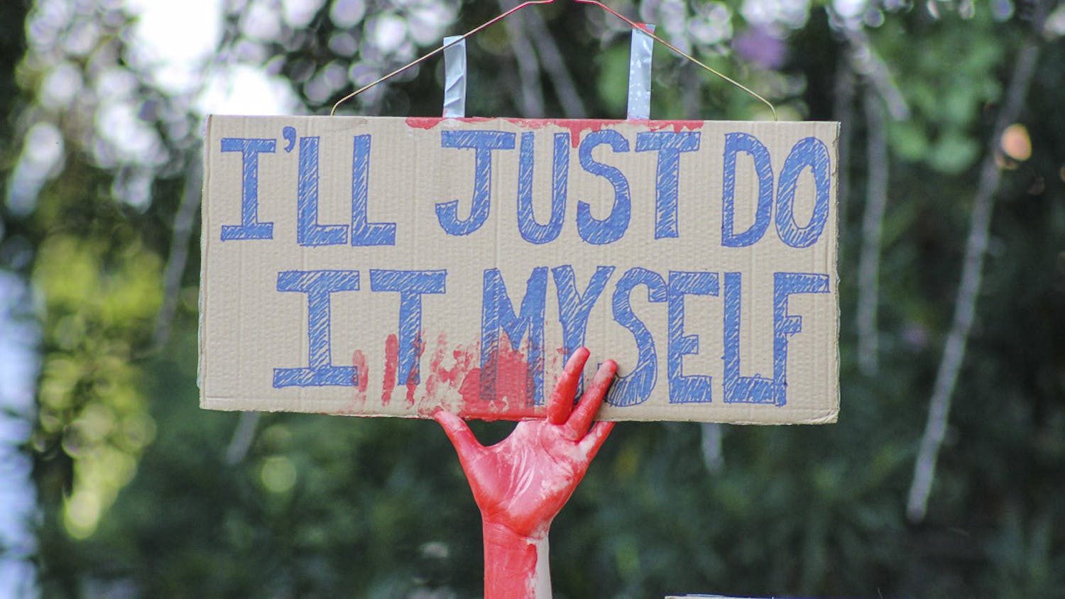 A protester covered in blood-colored paint holds up a pro-abortion sign labeled “I’ll Just Do It Myself” during the Dobbs v. Jackson protest at the South Carolina state capitol on June 25, 2022. The protest came as a response to the overturning of the landmark Roe v. Wade case earlier that June.