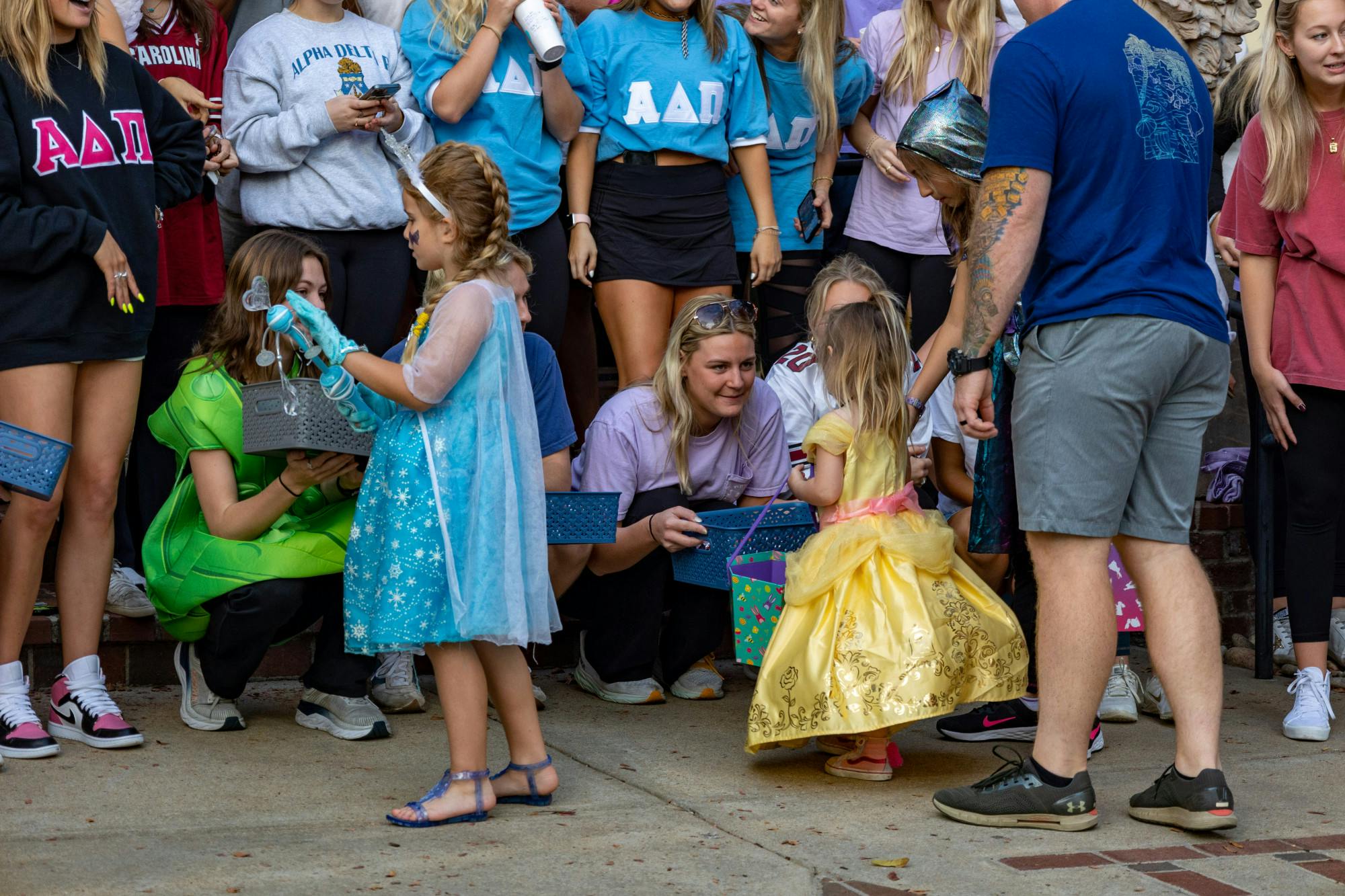 USC sorority sisters hand out candy to a pair of princess costumed trick or treaters during their Trick or Treat with the Greeks community event on Oct. 25, 2022. USC Greek fraternities and sorority gathered together in Greek Village with community members for games, fun activities and trick or treating.