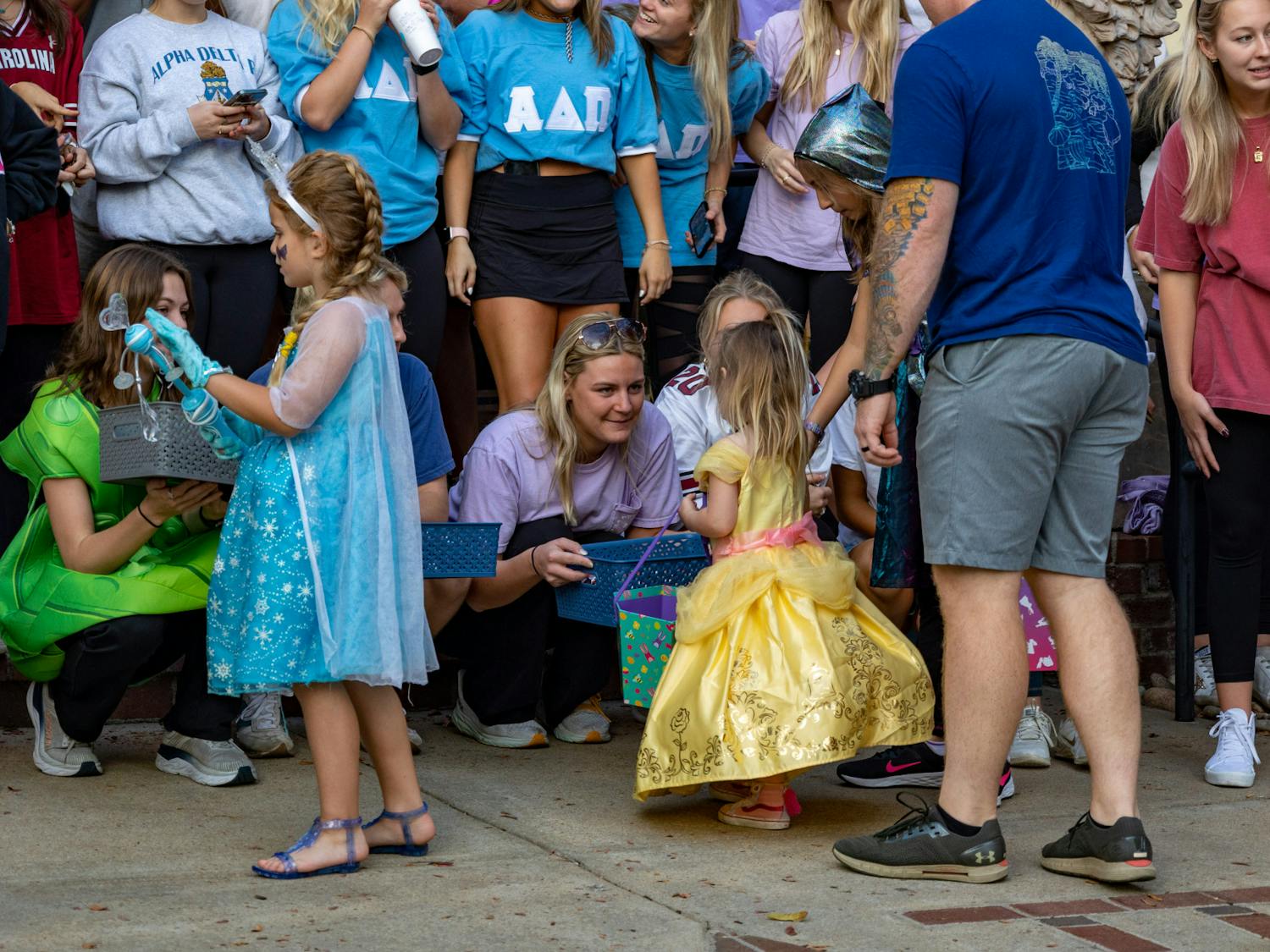 USC sorority sisters hand out candy to a pair of princess costumed trick or treaters during their Trick or Treat with the Greeks community event on Oct. 25, 2022. USC Greek fraternities and sorority gathered together in Greek Village with community members for games, fun activities and trick or treating.