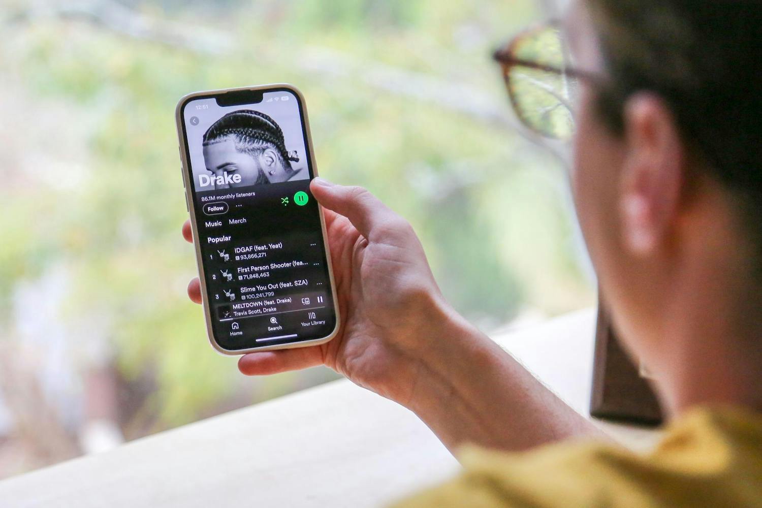 A photo illustration of a person holding a phone with Drake's music page opened through the streaming app Spotify on Oct. 31, 2023. Drake's newest album "For All the Dogs" debuted at No. 1 on the Billboard 200.