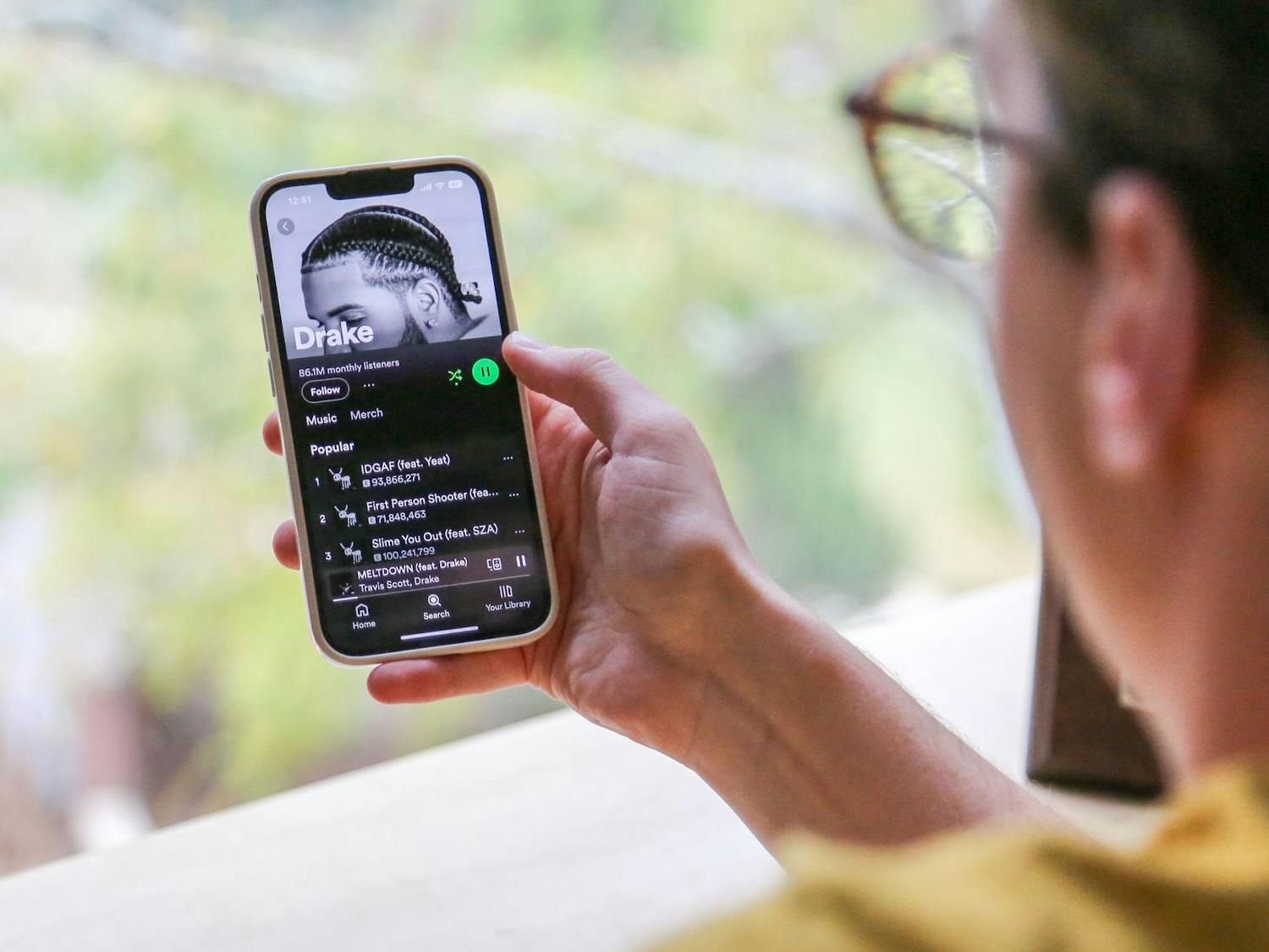 A photo illustration of a person holding a phone with Drake's music page opened through the streaming app Spotify on Oct. 31, 2023. Drake's newest album "For All the Dogs" debuted at No. 1 on the Billboard 200.