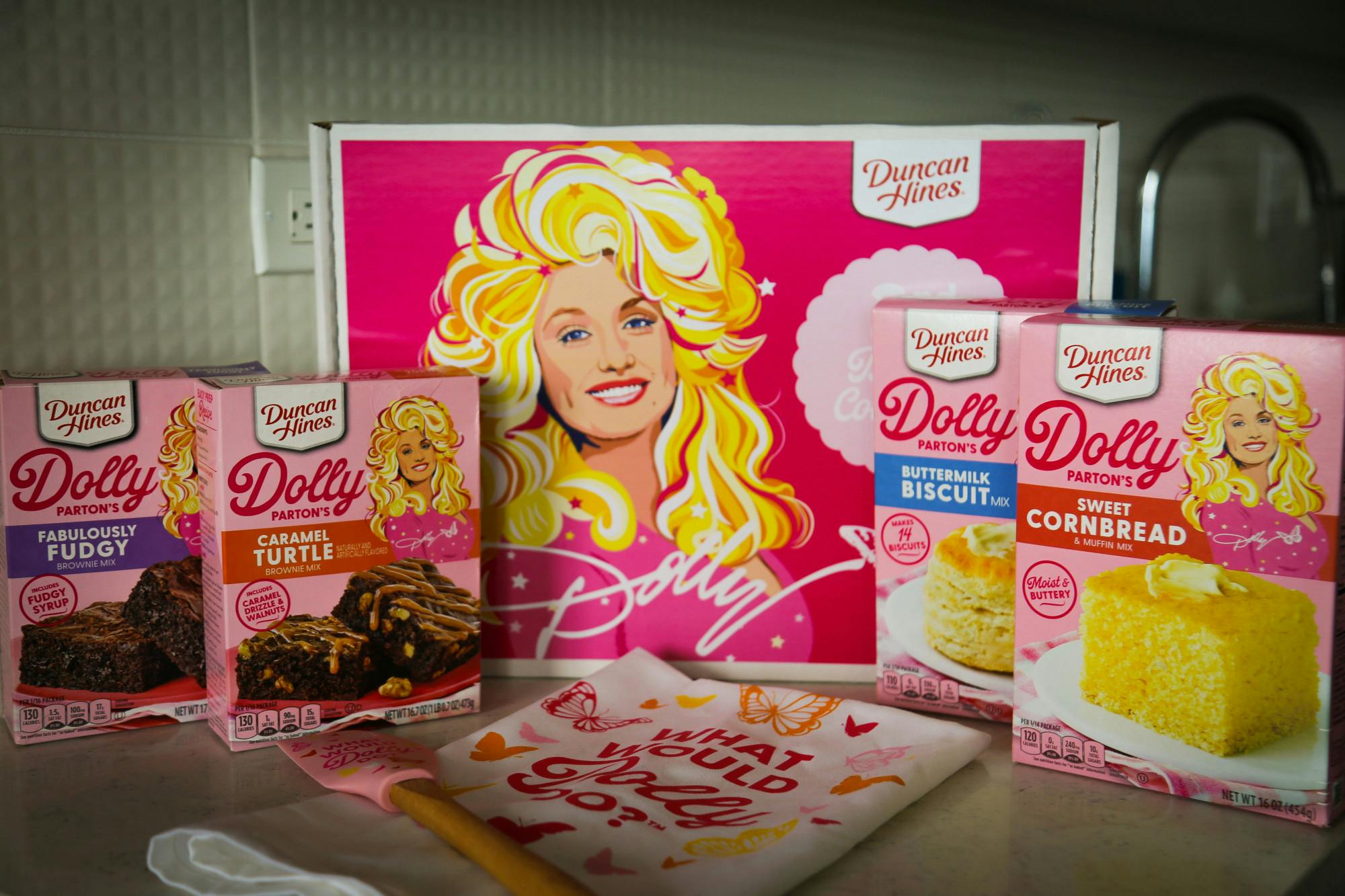 A photo illustration of Duncan Hines' Dolly Parton Baking Collection on Feb. 22, 2023. The kit was released early this month and includes two types of brownie mixes, a cornbread mix, a biscuit mix, a matching towel and spatula and collectible recipe cards.