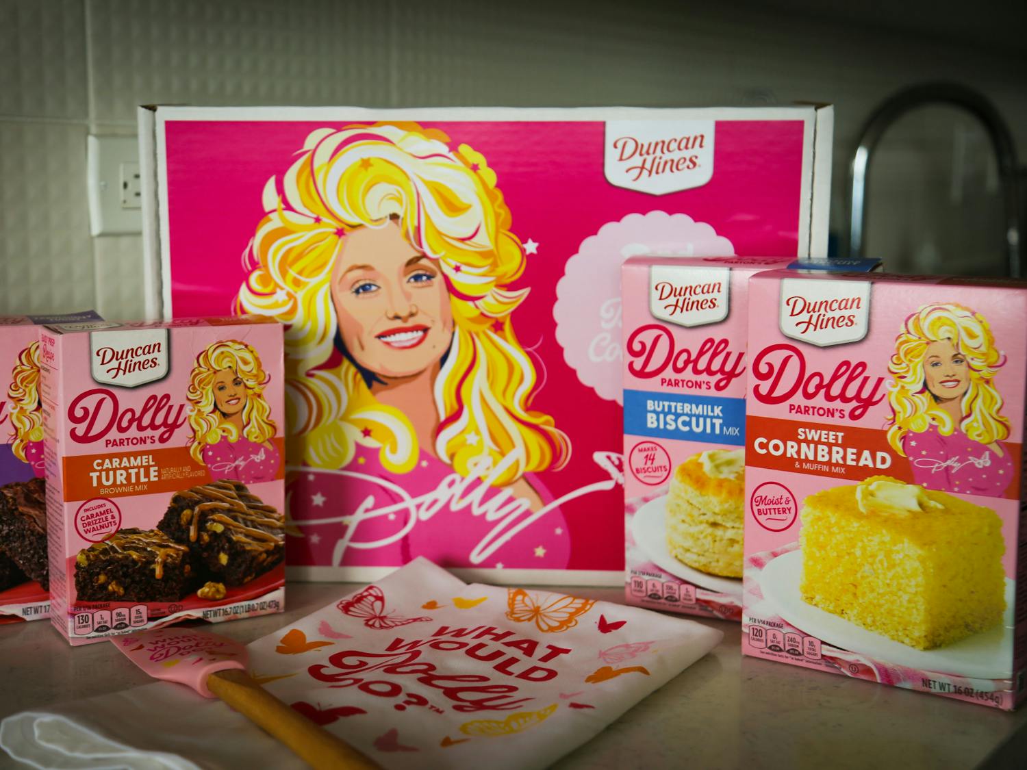 A photo illustration of Duncan Hines' Dolly Parton Baking Collection on Feb. 22, 2023. The kit was released early this month and includes two types of brownie mixes, a cornbread mix, a biscuit mix, a matching towel and spatula and collectible recipe cards.