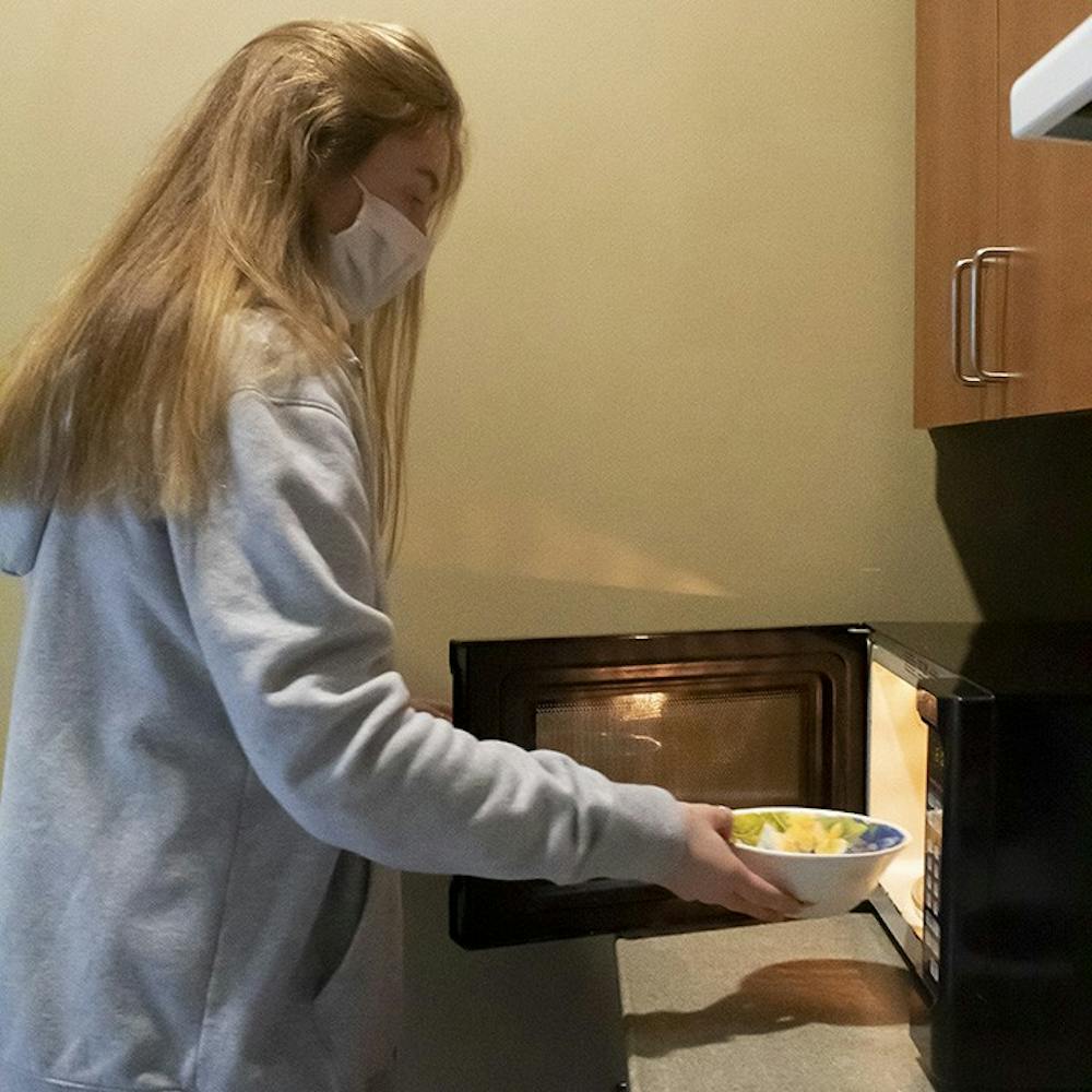 Second-year psychology student Gillian Porter puts a snack in the microwave at the Honors Residence Hall community kitchen.