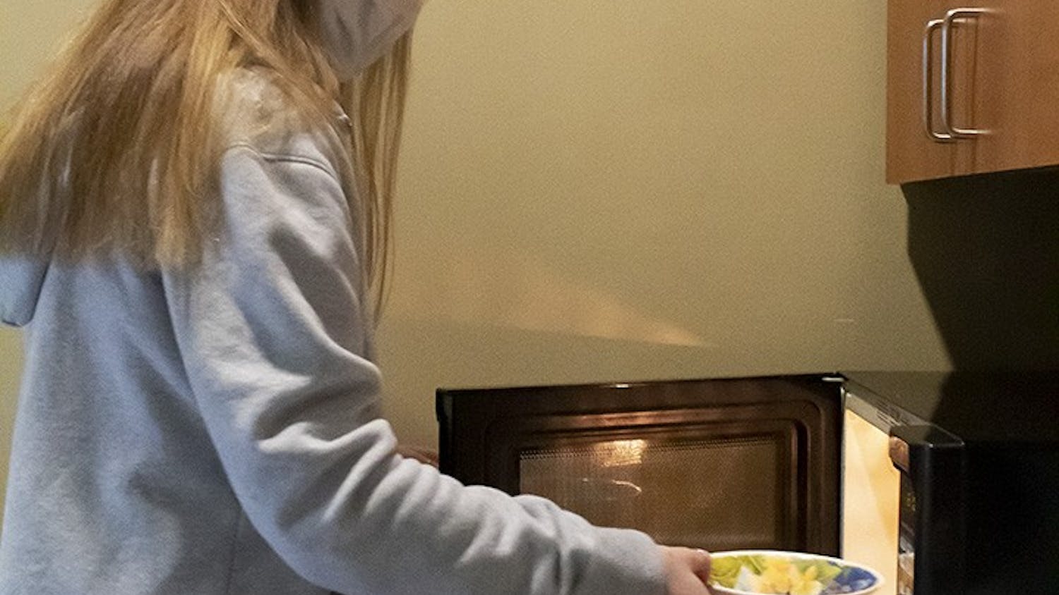 Second-year psychology student Gillian Porter puts a snack in the microwave at the Honors Residence Hall community kitchen.