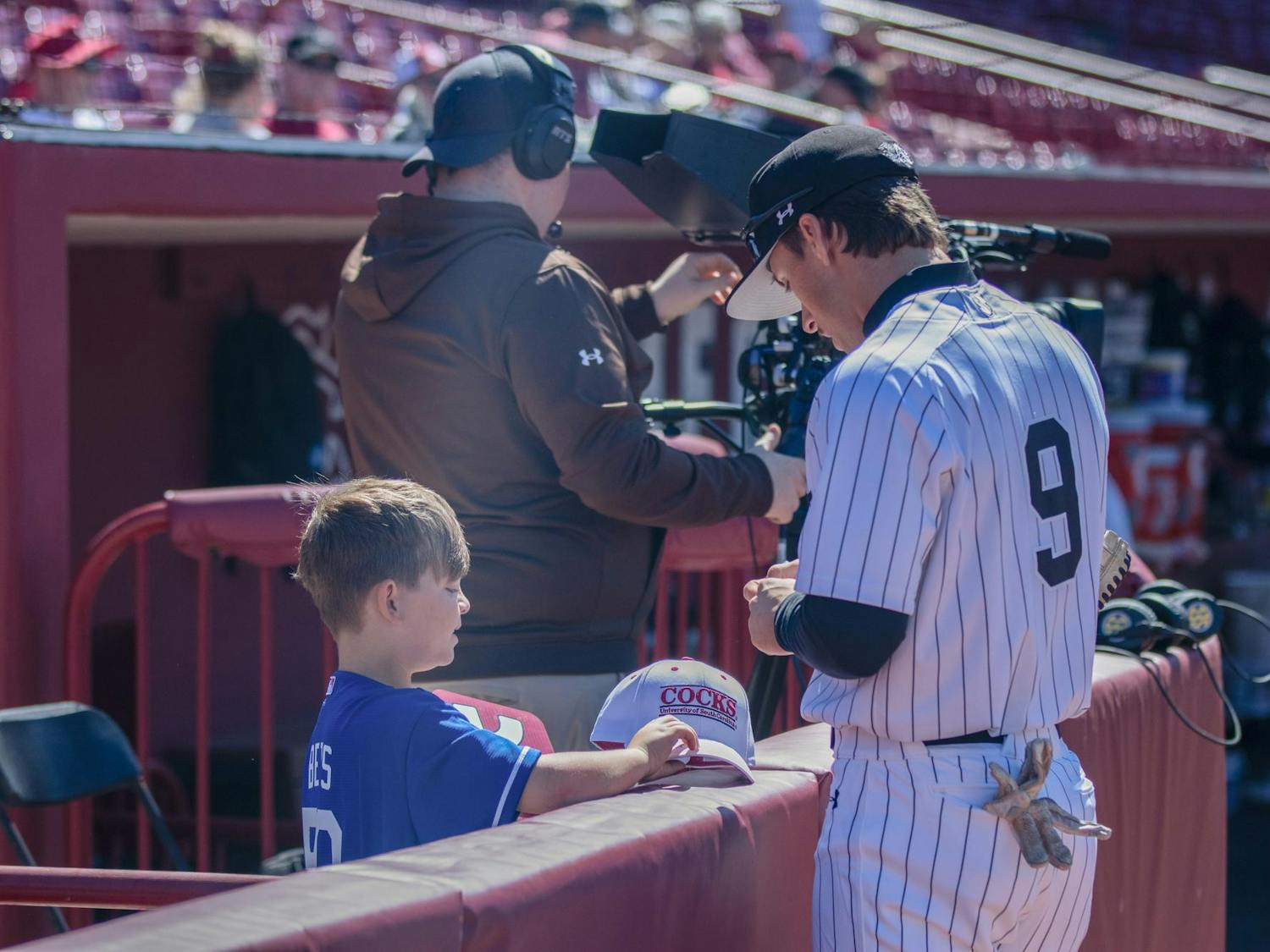 Junior outfielder Evan Stone autographs a young fan’s hat before South Carolina's game against Texas A&amp;M on April 6, 2024. Stone joined the Gamecocks as a freshman in 2022.