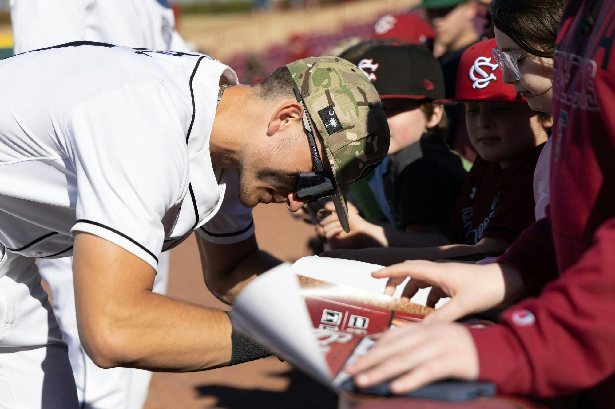 A Gamecock baseball player signs autographs for young fans after 8-0 defeat against Sacred Heart in Founder's Park on Feb. 16, 2025. The Gamecocks celebrated opening weekend with great weather in their final game after a rainy weekend in Columbia, South Carolina.