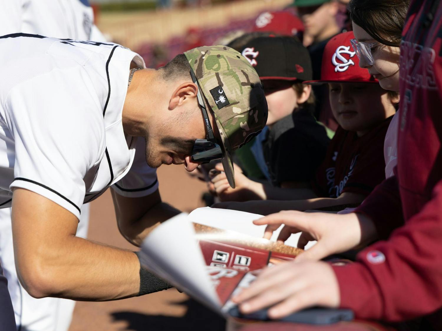 A Gamecock baseball player signs autographs for young fans after 8-0 defeat against Sacred Heart in Founder's Park on Feb. 16, 2025. The Gamecocks celebrated opening weekend with great weather in their final game after a rainy weekend in Columbia, South Carolina.