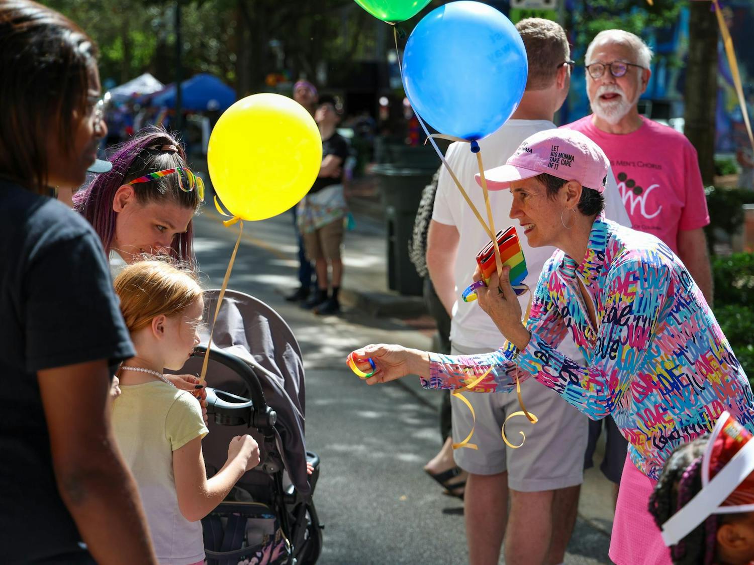 A volunteer with Big Momma Box gives a rainbow wrist band to a child on Main Street during the Famously Hot SC Pride Festival on Oct. 4, 2025. Numerous business and activist groups set up tents and tables on Main Street for the festival.