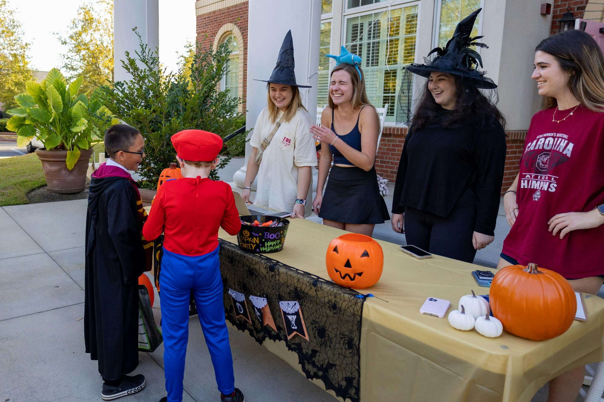 Sorority members hand out candy and compliment the costumes of two young trick or treaters during the Trick or Treat with the Greeks community event on Oct. 25, 2022. USC Greek fraternities and sororities came together to welcome community members to Greek Village for an evening of games, fun activities, unity and trick or treating.