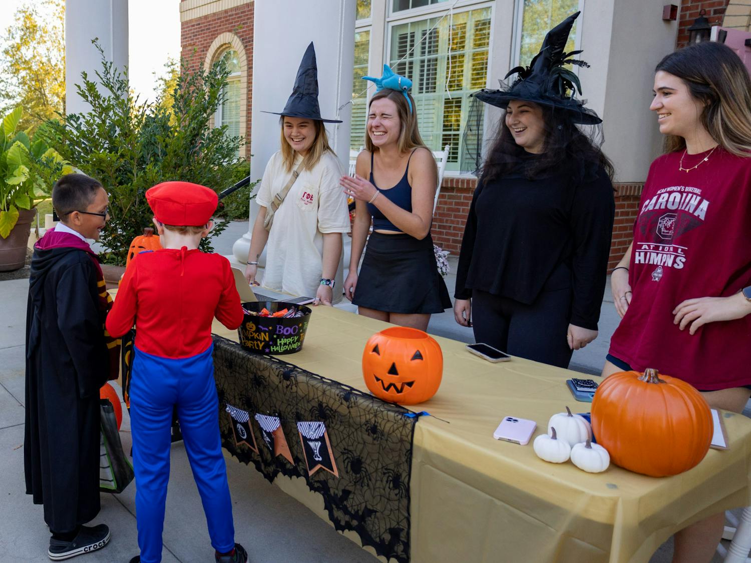Sorority members hand out candy and compliment the costumes of two young trick or treaters during the Trick or Treat with the Greeks community event on Oct. 25, 2022. USC Greek fraternities and sororities came together to welcome community members to Greek Village for an evening of games, fun activities, unity and trick or treating.