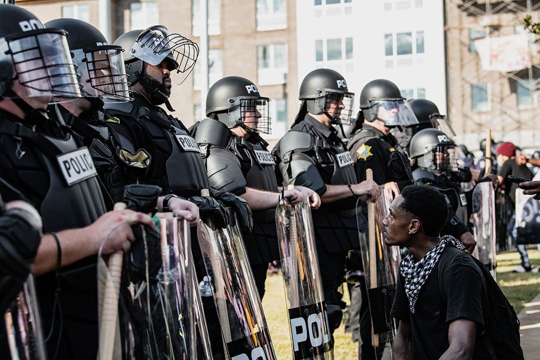 A photograph by Crush Rush, one of the five photo journalists featured at the Hindsight 2020 exhibit, which features pictures of events that defined 2020. This popular image captures a protestor kneeling and looking up at a Black police officer at a police brutality protest at the Statehouse following the death of George Floyd.