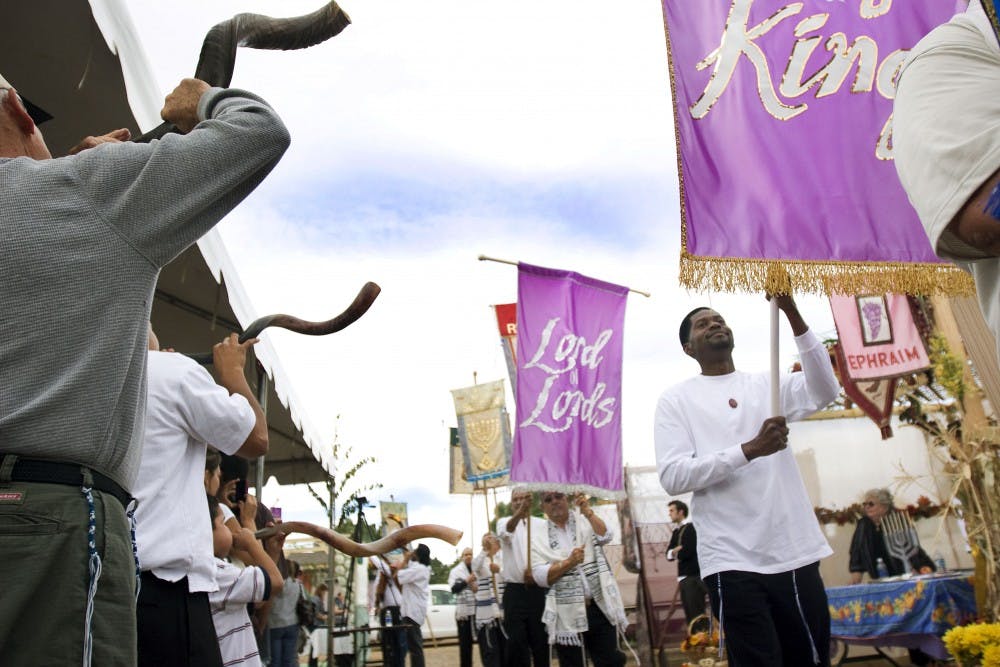 	Banner carriers walk in front of the Olive Tree Messianic Temple Saturday to celebrate Sukkot, a Jewish feast day. This is the fifth annual celebration at Olive Tree of the Feast of Tabernacles, which commemorates the Jewish pilgrimage to Jerusalem.