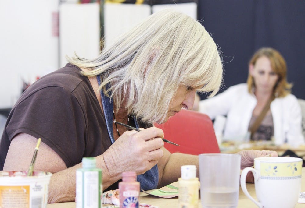 Beverley Sovereign works on a watercolor sunflower on Tuesday afternoon at the OffCenter Community Arts Studio. Beverley has been frequenting the art studio for four years and believes the arts studio has, "helped her grow as an artist." 