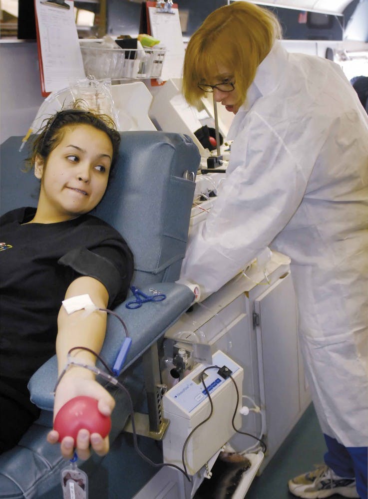 Student Crystal Otero looks over her shoulder while United Blood Services supervisor Carol Sylverter prepares to finish the blood donation process Monday in the organization's mobile donation center parked in front of the SUB. Sylverter said the process t
