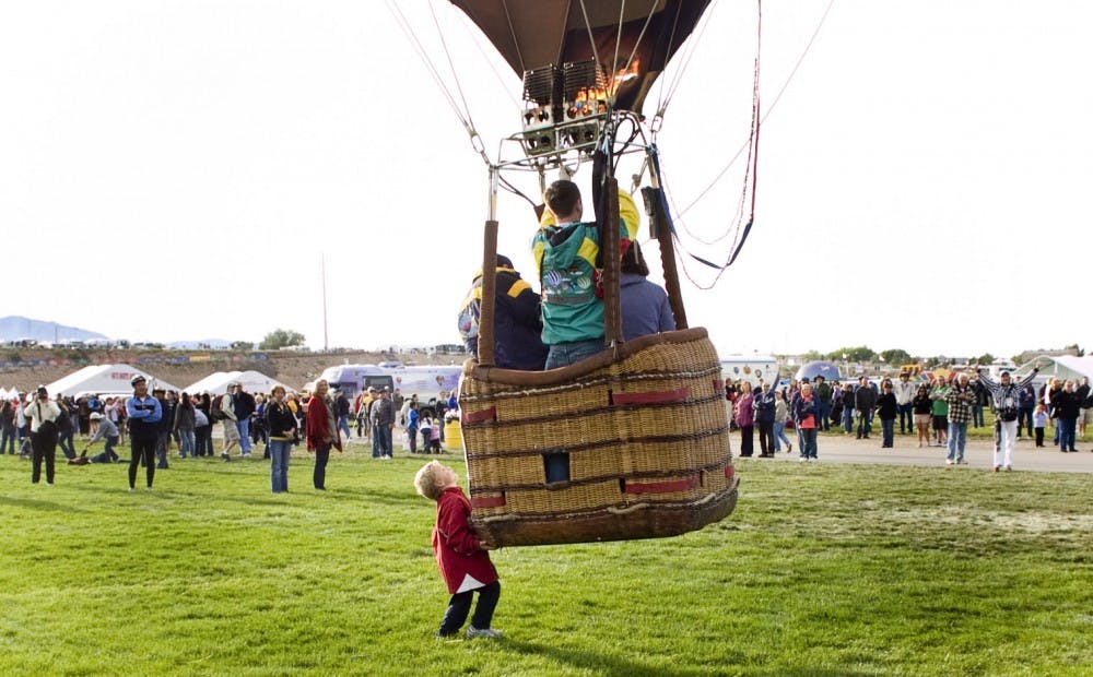 	Pilot Mark Trillanes directs his balloon upward as his son, Anthony, pushes on his father’s gondola during lifto at the
balloon  esta. Several UNM students said the annual event has lost some of its appeal and many will not attend.