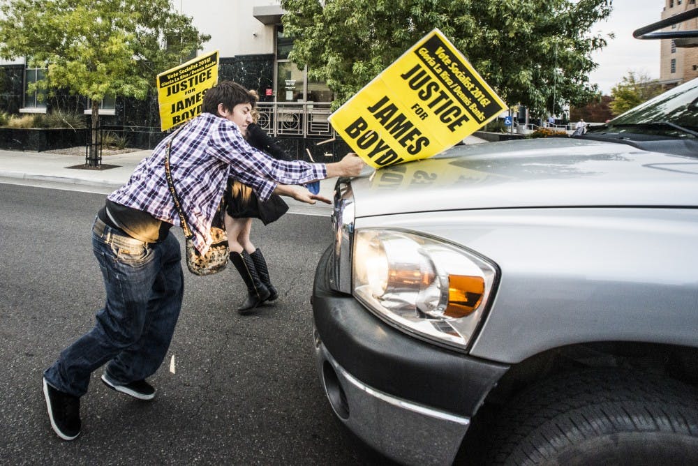 Protester Benjamin Imbus strikes the hood of a vehicle after the driver pushed through a line of demonstrators on Lomas Boulevard in Albuquerque, New Mexico.