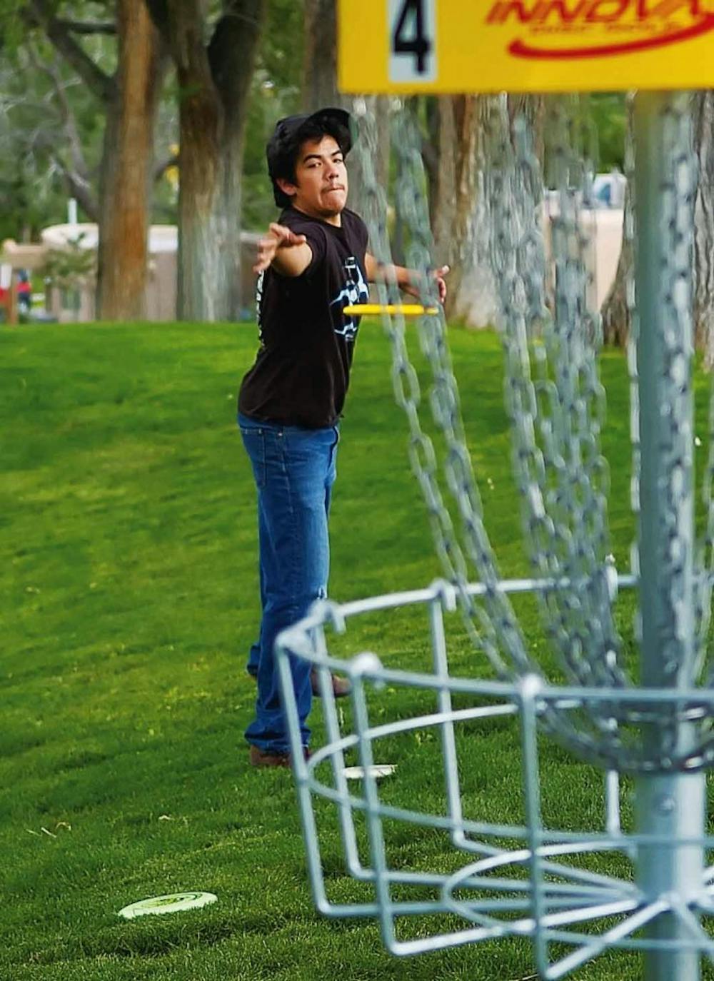 UNM student Bobby Perea throws a disc at the fourth hole of Roosevelt Park's disc golf course June 22. The park reopened last week after being closed since September for renovation. 