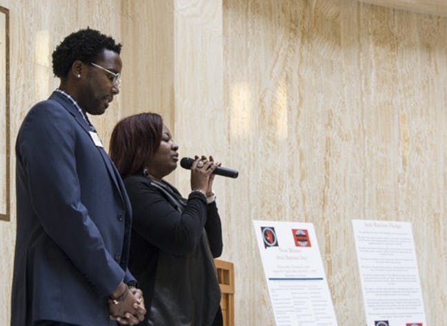 Hakim Bellamy (left) bows his head while Rosalind Jones sings Amazing Grace Wednesday, Feb. 3, 2016 in the New Mexico Capitol's Rotunda during an Anti-Racism Day event.