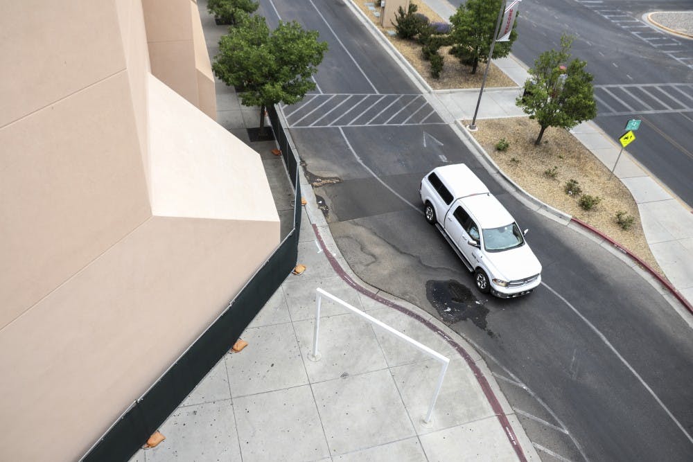 A car drives into the UNM Cornell parking structures and passes by a row of fences blocking off Johnson Gym in preparation for upcoming construction on June 3, 2018.