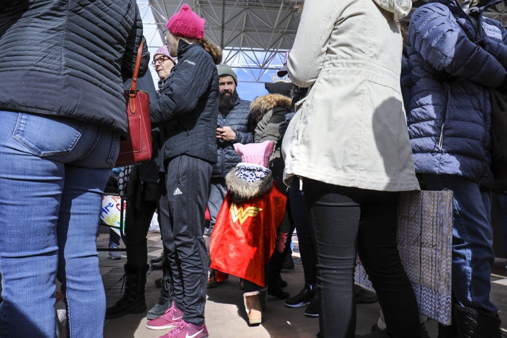 A young girl wearing a Wonder Woman cape wonders through a crowd of women during the women?s march at the Civic Plaza on Sunday afternoon.  