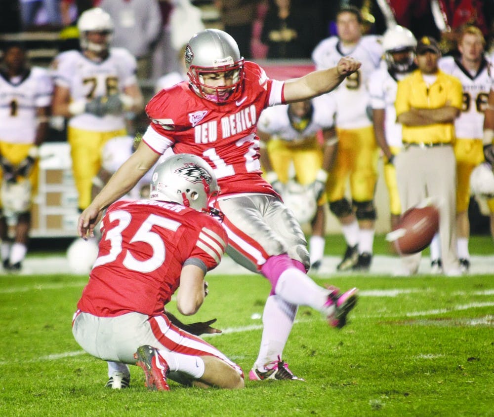 	The UNM football team’s placeholder Ben Skaer places the football for Lobo kicker James Aho on Saturday. The 38-yard attempt was good as time expired and the Lobos defeated Wyoming 34-31 at University Stadium.   