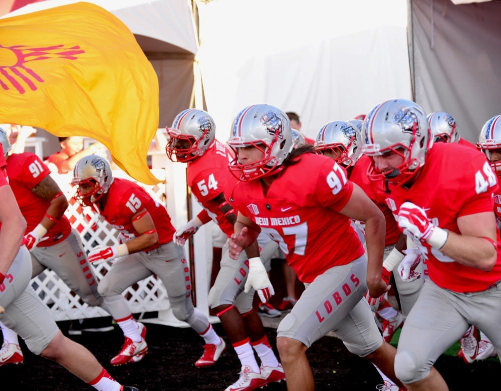 Steven Romero, #97, along with the rest of the Lobos charges out of the tunnel behind a New Mexico state flag during the opening of their game against Tulsa on Saturday, Sept. 12. The Lobos will play the Aggies this Saturday at University Stadium.