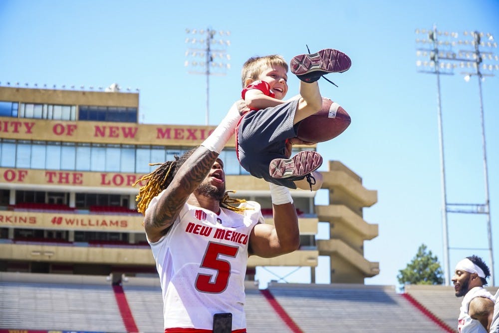 UNM Wide Reciever Patrick Reed aids kid during a relay race on Saturday 4/21 at University Stadium.