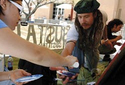 Heron Boyce, right, gets more paint from freshman Jenya Novgorodskaya to paint the community mural at UNM Sustain's information booth in front of the SUB on Wednesday. The group, also known as the UNM Campus Sustainability Forum, was chartered last August