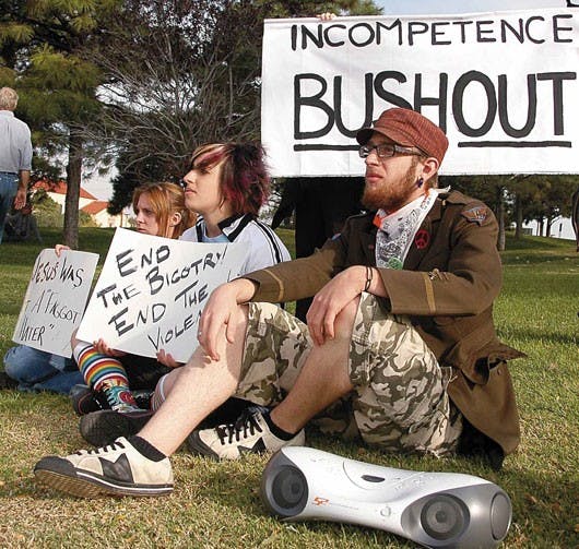 Protesters, from right, Jason Neel, Anna Neel and Lizzy Straba sit near the corner of Central Avenue and University Boulevard during the World Can't Wait demonstration Thursday. The event was part of a nationwide protest against President George Bush.