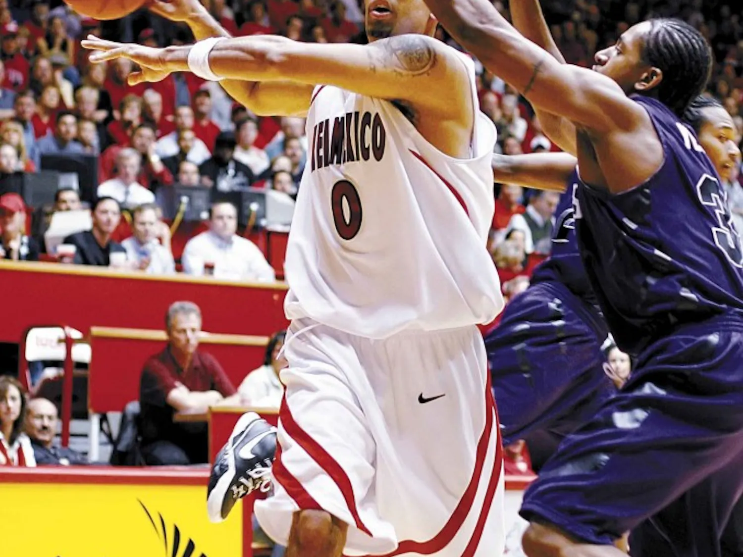 UNM forward Aaron Johnson passes the ball to a teammate while Kansas State's Deilvez Yearby defends during Tuesday's 78-54 win at The Pit.