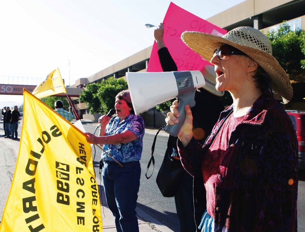 UNM Hospital social worker Cynthia Goldblatt yells into a megaphone during a protest at the hospital on June 1. The hospital workers picketed to raise awareness about employee wages.