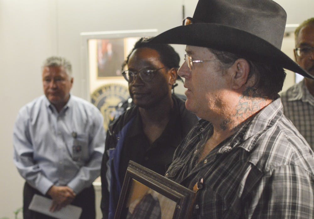 	Kenneth Ellis, father of Albuquerque Police shooting victim Kenneth Ellis III, holds a photo of his deceased son at the office of Mayor Richard Berry at City Hall on Wednesday afternoon. Several relatives of people shot and killed by APD came to City Hall to call on Mayor Berry to cancel a police shooting competition taking place next month.
