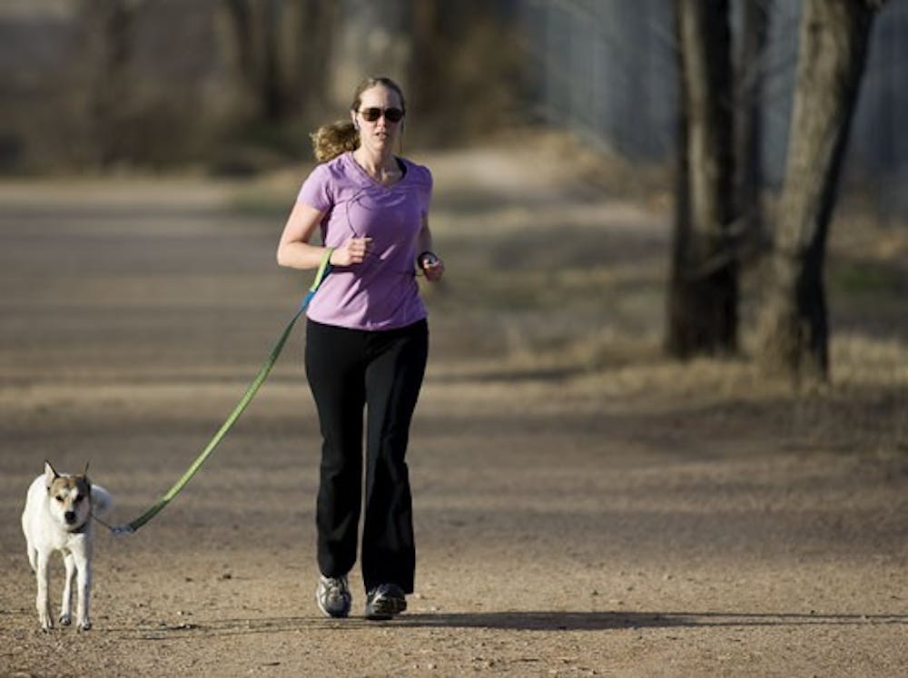 Christie McAuley runs with her dog, Griffin, on Thursday at the UNM North Golf Course. The fate of the golf course has been in question since February 2007, when the University expressed interest in developing the area into a retirement community for alum