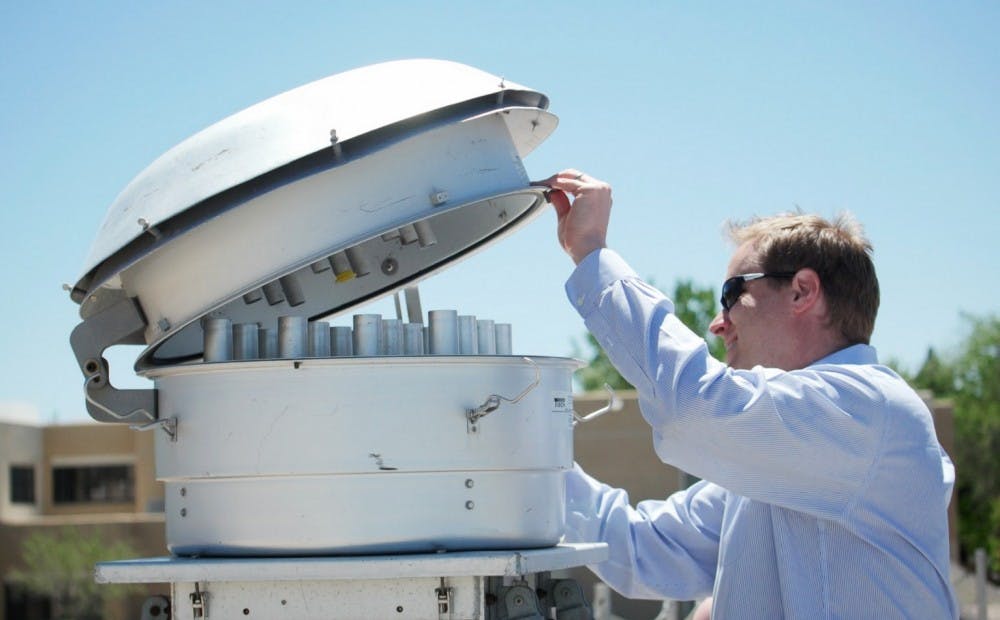 Matt Campen opens a wind receptacle tower to show how contaminated dust is captured for analysis on Friday, April 21, 2017 on UNM’s North Campus.