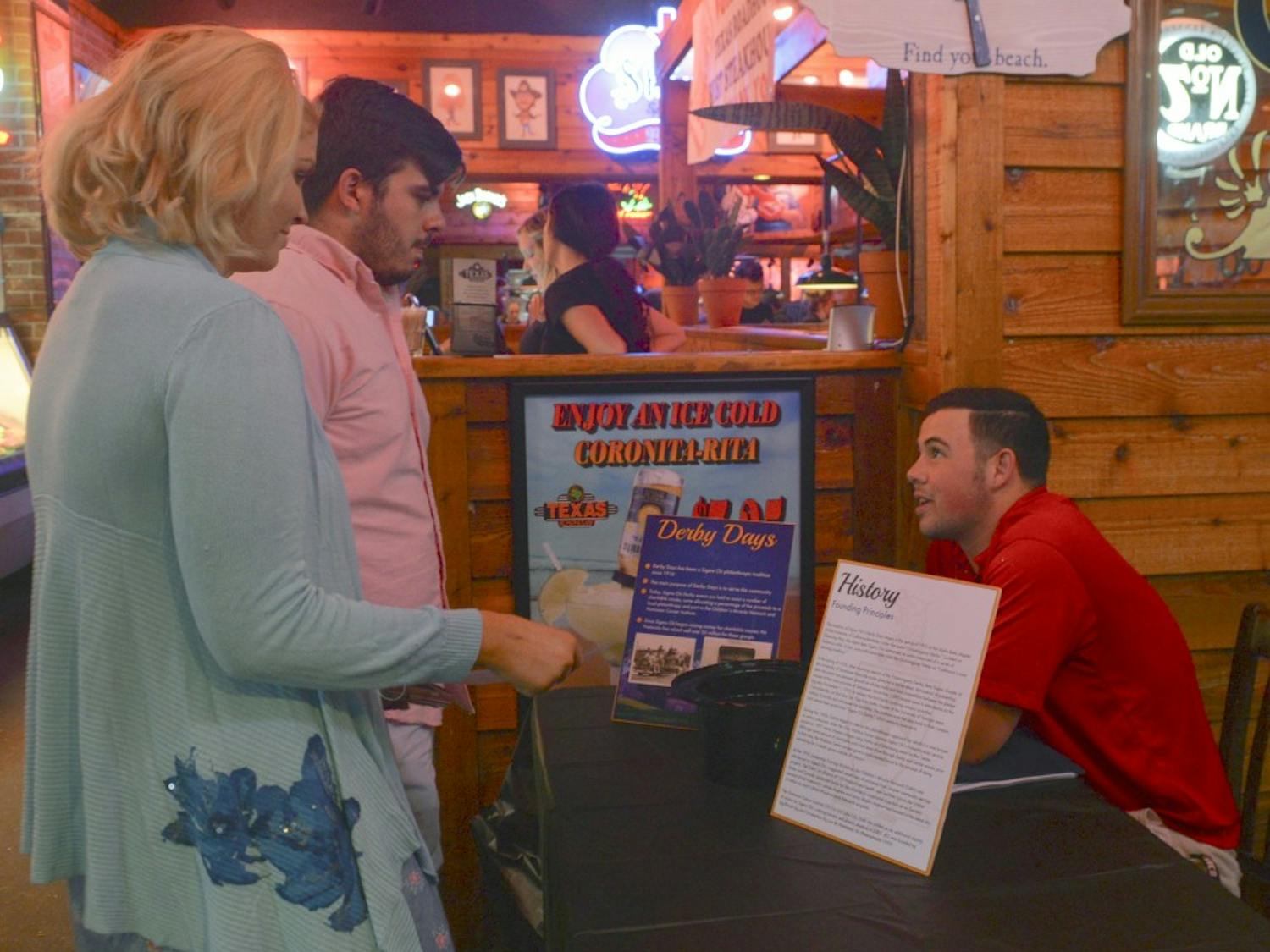 Vice President of UNM Sigma Chi Joe Trujillo talks to Jeff Dan Herrera, middle, and Liz OReilly, left, about their fundraising event that took place at the Texas Roadhouse Tuesday evening. Sigma Chi will hold different events throughout the week.