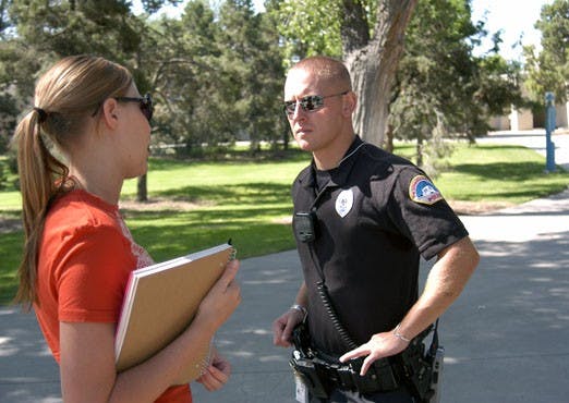 Officer Robert Rush and senior Bailey Snyder discuss campus safety concerns by a blue box near the Duck Pond. 