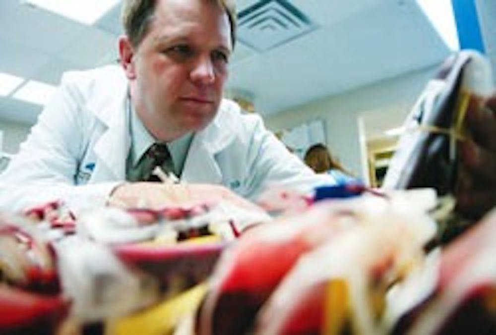 Dr. Kendall Crookston, director of transfusion medicine and coagulation, looks at labels on blood units in a refrigerator at UNM Hospital on Wednesday.